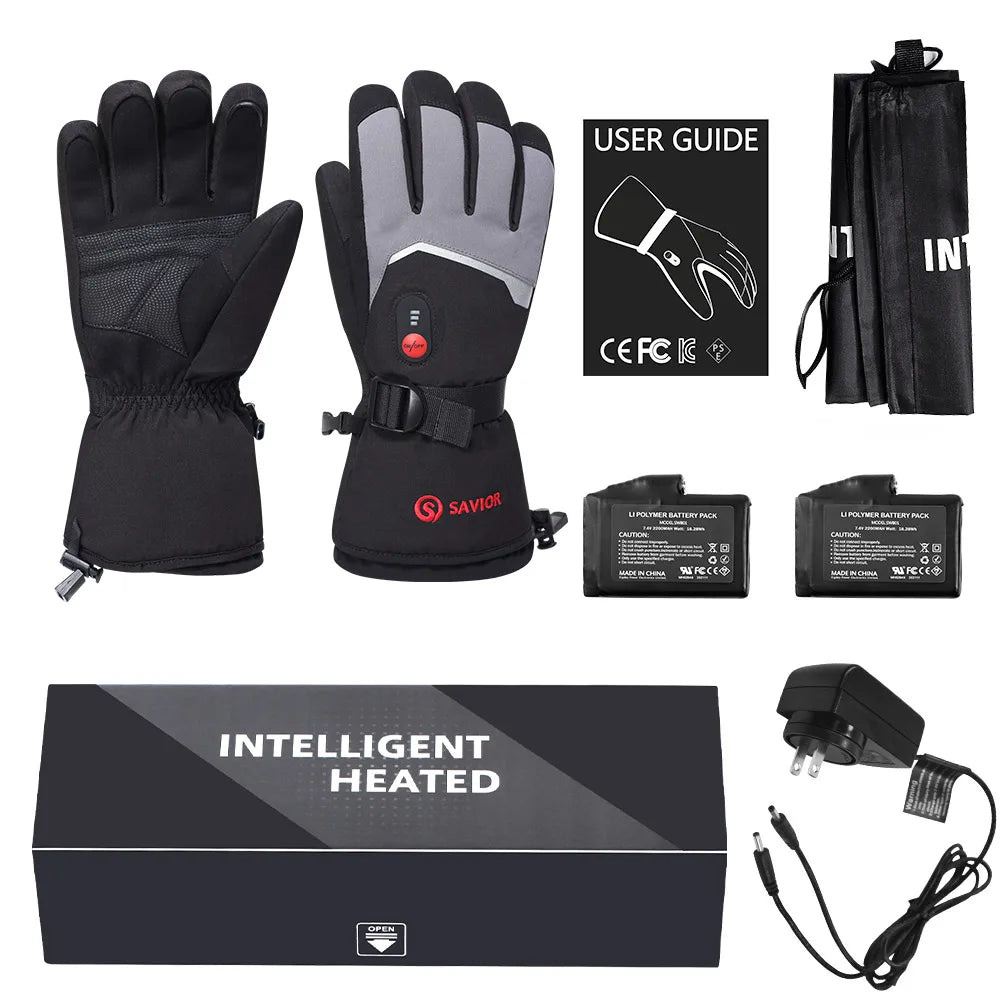 A set of black and gray heated winter gloves with a built-in controller, shown alongside a black carrying pouch, user guide, two batteries, a power adapter, and the product box on a white background.